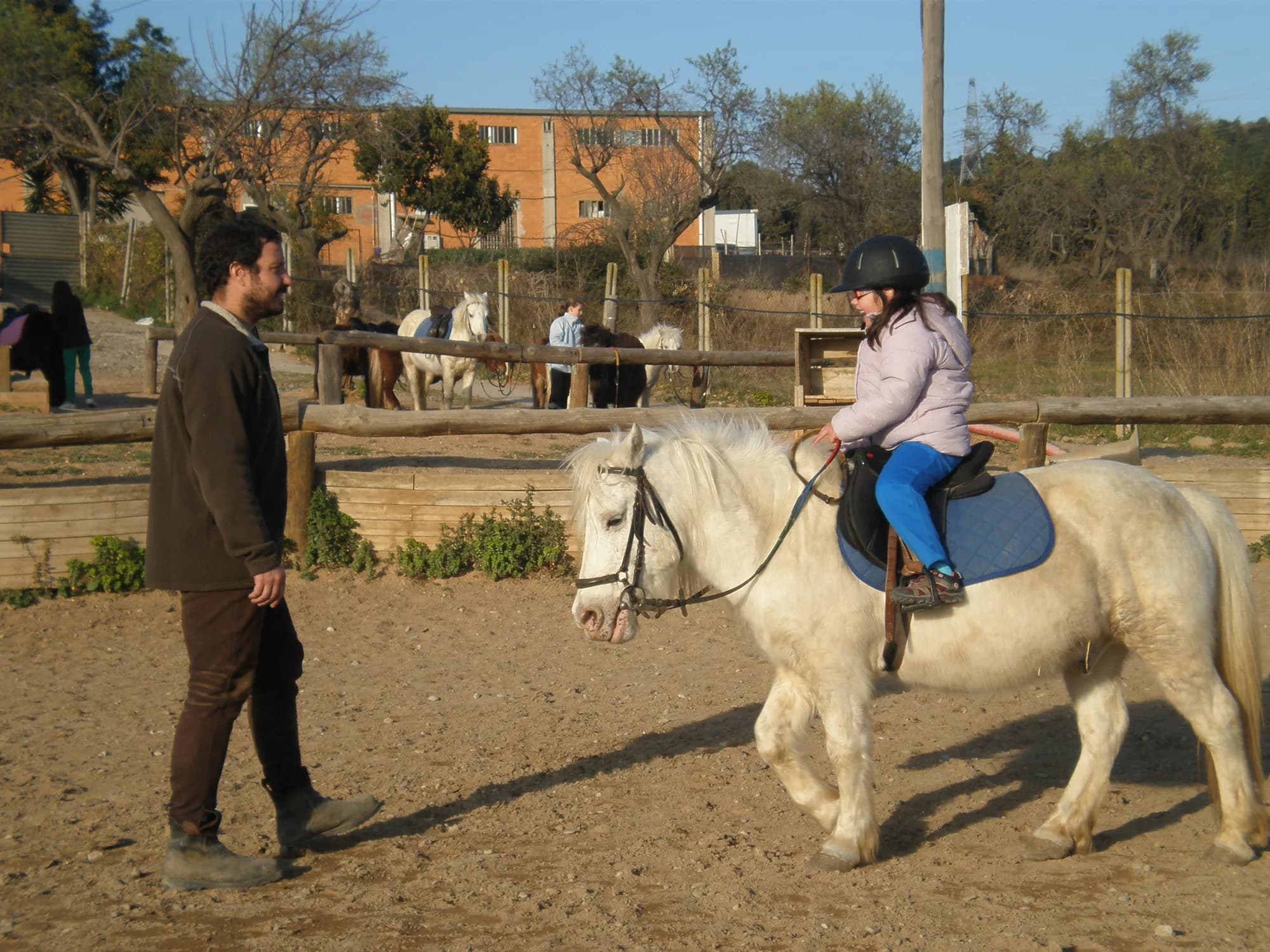 Sessió d'equinoteràpia amb una alumna sobre un poni blanc